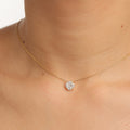 Gold necklace with a diamond Illusion pendant on a person's neck against a neutral background